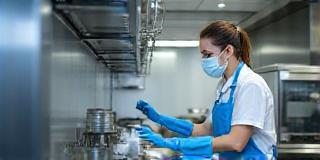 Cleaner working in kitchen with PPE